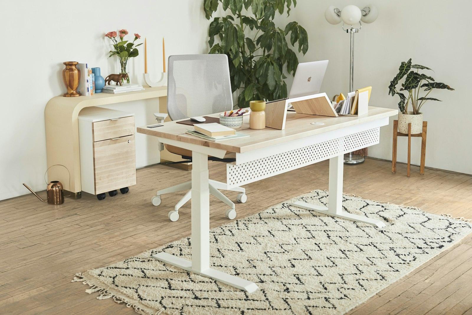 Ljust kontorshörn med skrivbord, stol och gröna växter